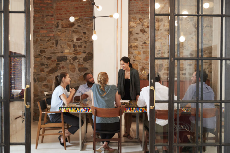 A diverse team of global entrepreneurs collaborating around a modern meeting room table, illustrating how to start a business in Mexico.